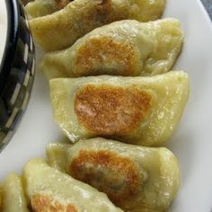 some dumplings are sitting on a plate next to a bowl of yogurt