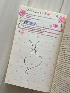 an open book with a drawing of a kissing couple on the page and pink flowers