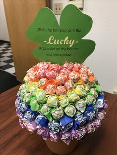 a potted plant filled with candy on top of a wooden table next to a sign that says, pick the lelipop with the lucky green dot on the bottom