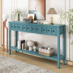 a blue console table with two drawers and some books on it in a living room