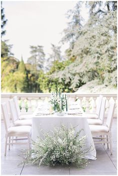 the table is set with white linens and greenery for an outdoor wedding reception