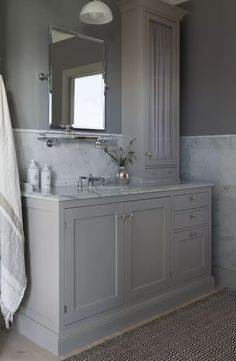 a bathroom with gray cabinets and marble counter tops