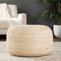 a large round jute ottoman sits on the floor in front of a white couch