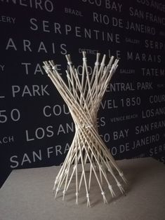 a sculpture made out of sticks sitting on top of a table next to a wall