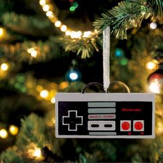 an ornament hanging from a christmas tree decorated with lights and a video game controller