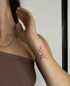 a woman with a small tattoo on her left arm holding onto the other side of her neck