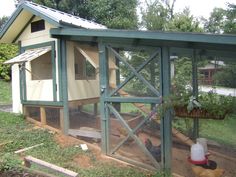 a chicken coop with two chickens in it's pen and one on the ground