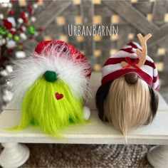 two wigs sitting on top of a white table next to each other with christmas decorations in the background