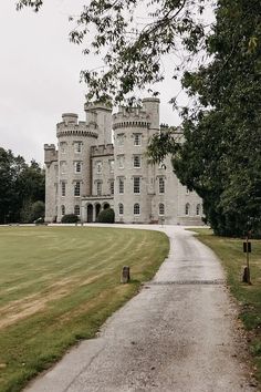 a large castle like building sitting on top of a lush green field next to a dirt road