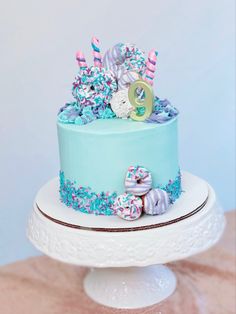 a blue cake with sprinkles and decorations on it sitting on a table