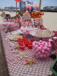 pink and white desserts on a beach with umbrellas in the backgroud