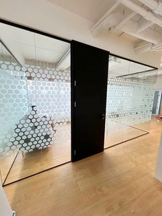 an empty room with glass partitions and wood flooring in front of the doors