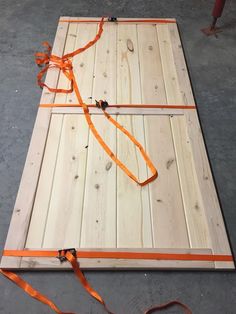 a piece of wood with orange ribbon tied around it on top of cement flooring