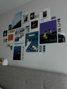 a bed with a gray headboard and lots of pictures on the wall above it