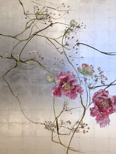 some pink flowers are in a vase on a white tablecloth with silver foil behind it