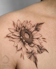 a sunflower tattoo on the back of a woman's shoulder