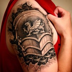 a man with a dragon tattoo on his arm and shoulder is holding onto a book