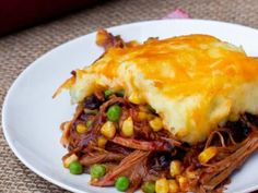 a white plate topped with meat and veggies covered in cheese