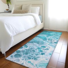 a bedroom with a bed, rug and window in the background is seen on a hardwood floor