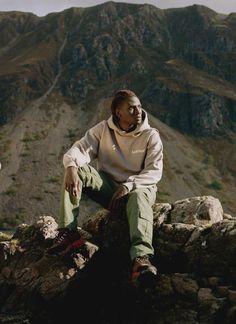 a man sitting on top of a rock next to a mountain