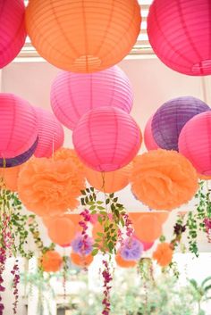 many pink and orange paper lanterns hanging from the ceiling