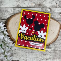 a red and white card with mickey mouses on it next to some lilies