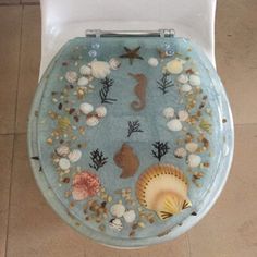 a blue toilet seat with sea shells and seashells on it