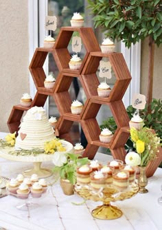 a table topped with lots of cupcakes next to a wooden hexagon