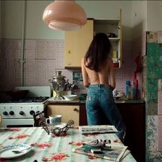 a woman standing in a kitchen next to a table with utensils on it