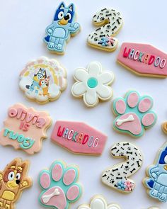 there are many decorated cookies on the white table with name tags and dog paw prints