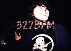 a woman with glasses and a skull on her shirt in front of a dark background