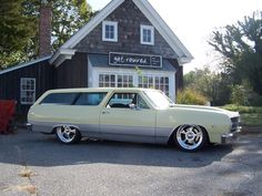 an old station wagon is parked in front of a small building with a sign on it