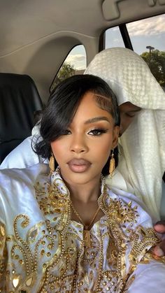 a woman sitting in the back seat of a car wearing gold and white clothing with an elaborate head piece