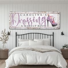 a bed with white sheets and pillows in front of a sign that says carolina's dressing & makeup room