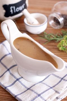 a gravy in a white gravy dish on top of a blue and white towel