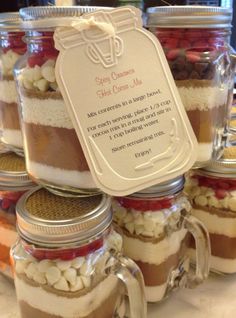 jars filled with different types of desserts on top of a white tablecloth covered table