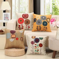 three pillows on a couch with flowers in the middle and one sitting on a chair