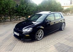 a black car parked in front of some trees