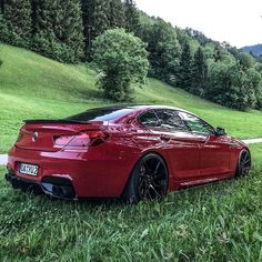 a red sports car parked on the side of a road next to a lush green hillside