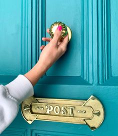 a person's hand holding a door handle on a blue door with a post