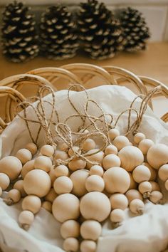 a basket filled with lots of white eggs on top of a table next to pine cones