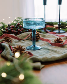 a table with pine cones, candles and napkins on it is decorated for christmas