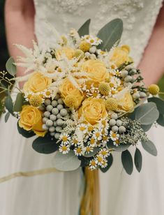 a bridal bouquet with yellow flowers and greenery