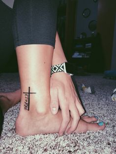 a person with a cross tattoo on their foot is sitting on the floor next to another person