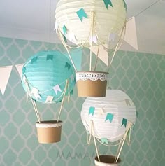 three paper hot air balloons hanging from the ceiling in a room with blue and white wallpaper