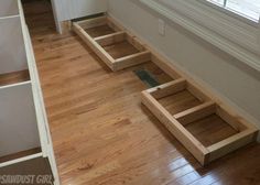 an empty room with wooden flooring and drawers on the bottom level, in front of a window