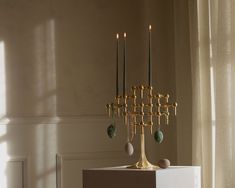 a gold candelabra sitting on top of a white pedestal in front of a window