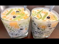 two glasses filled with fruit on top of a table