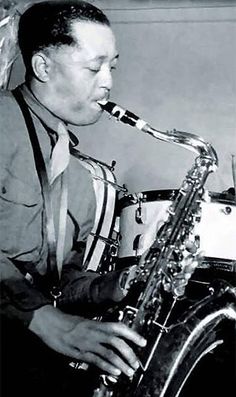 two men are playing instruments in an old black and white photo, one man is smiling at the camera