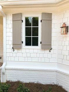 a white brick house with shutters on the windows